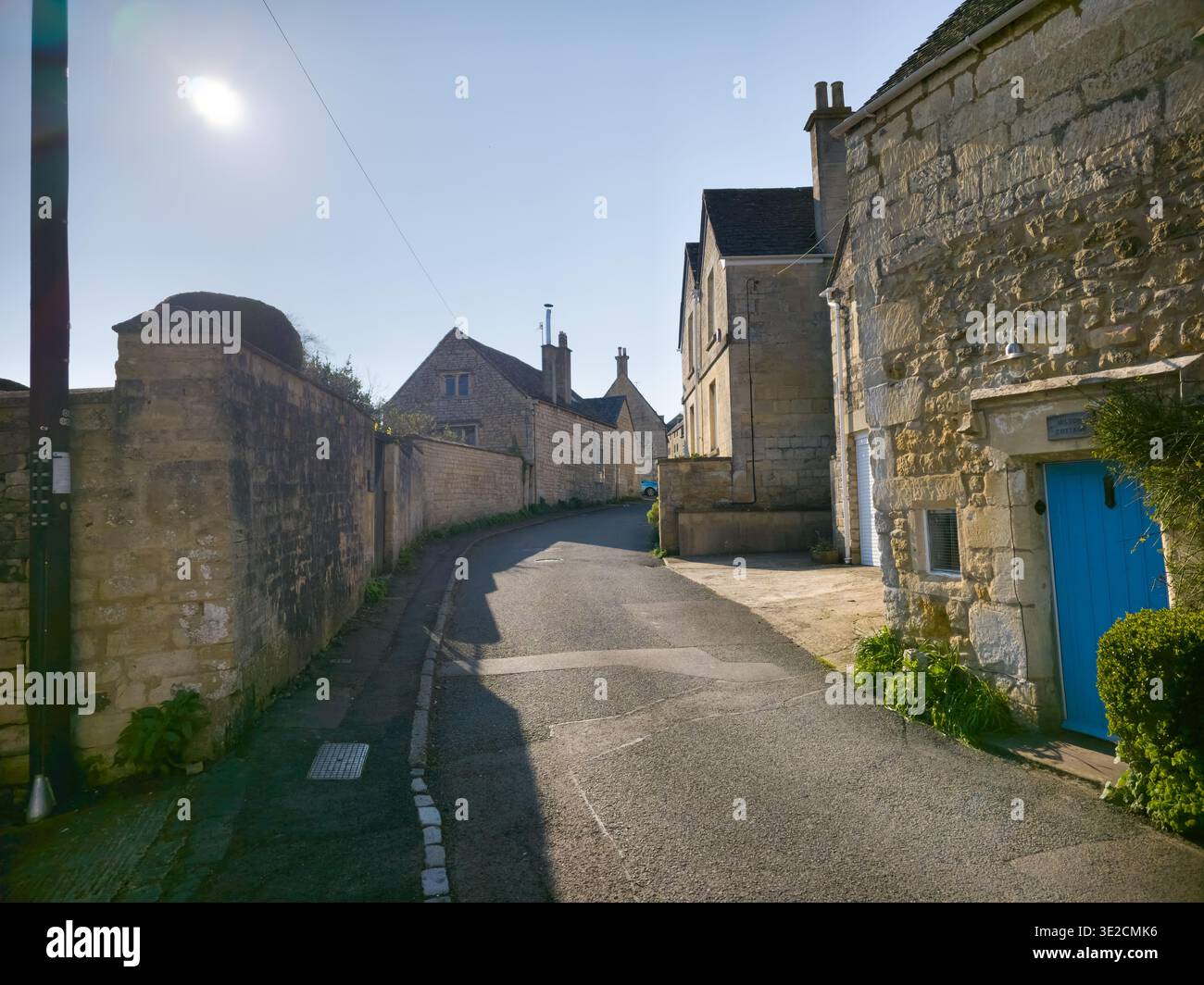 Sunlit Narrow Cotswold Lane avec Honey Stone Houses et Lens Flare, Painswick Area, Gloucestershire, Angleterre - Image de stock capturée avec un smartphone