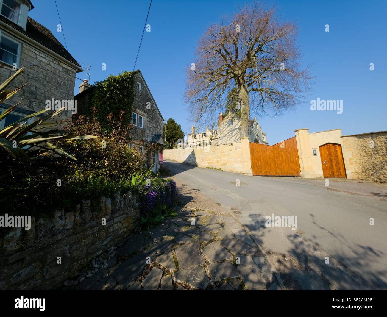 Sunlit Narrow Cotswold Lane avec Honey Stone Houses et Lens Flare, Painswick Area, Gloucestershire, Angleterre - Image de stock capturée avec un smartphone