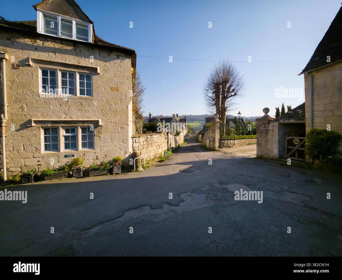 Sunlit Narrow Cotswold Lane avec Honey Stone Houses et Lens Flare, Painswick Area, Gloucestershire, Angleterre - Image de stock capturée avec un smartphone