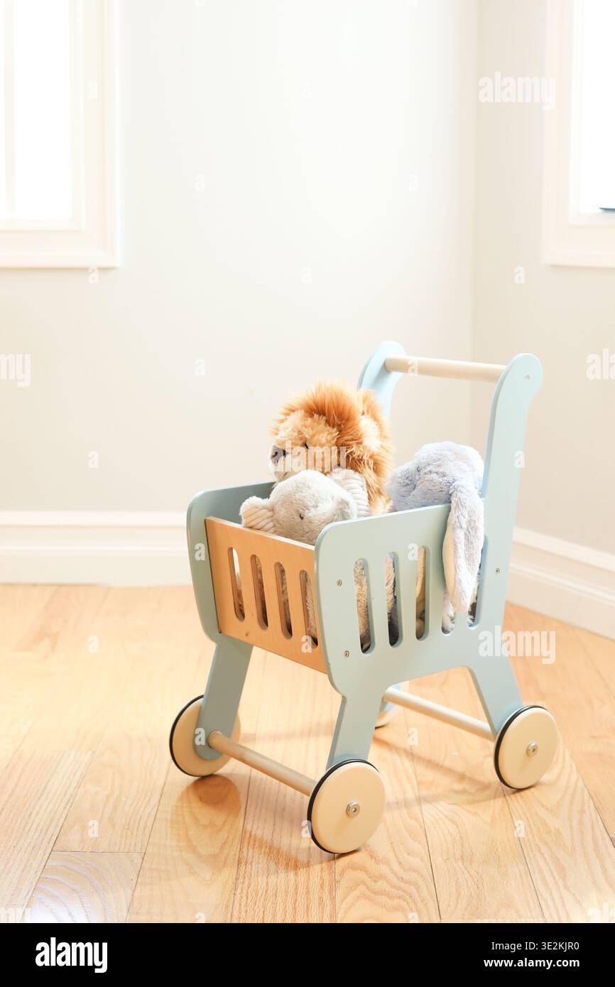 Chariot en bois avec animaux en peluche dans une pièce lumineuse Banque D'Images