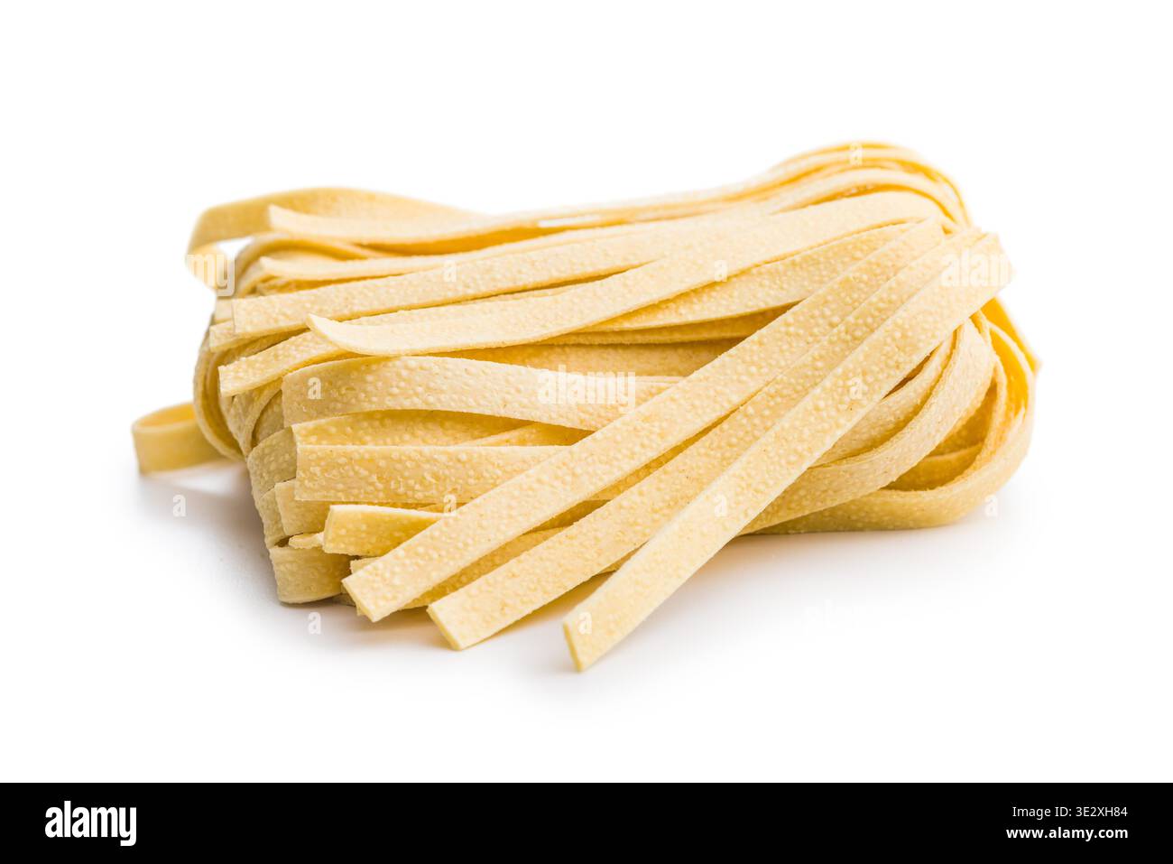 Les brins de pâtes fettuccine reposent sur une surface blanche, paraissant doux et frais. Ce type de pâtes est souvent utilisé dans divers plats. Banque D'Images