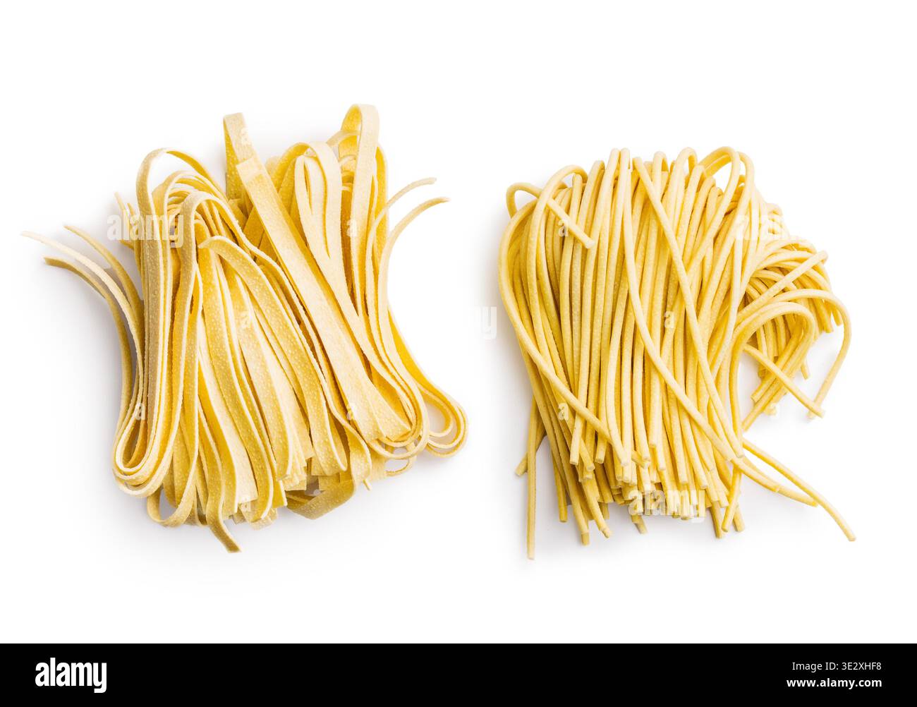 Des brins de fettuccine et de bigoli reposent sur une surface blanche, paraissant doux et frais. Ce type de pâtes est souvent utilisé dans divers plats. Banque D'Images