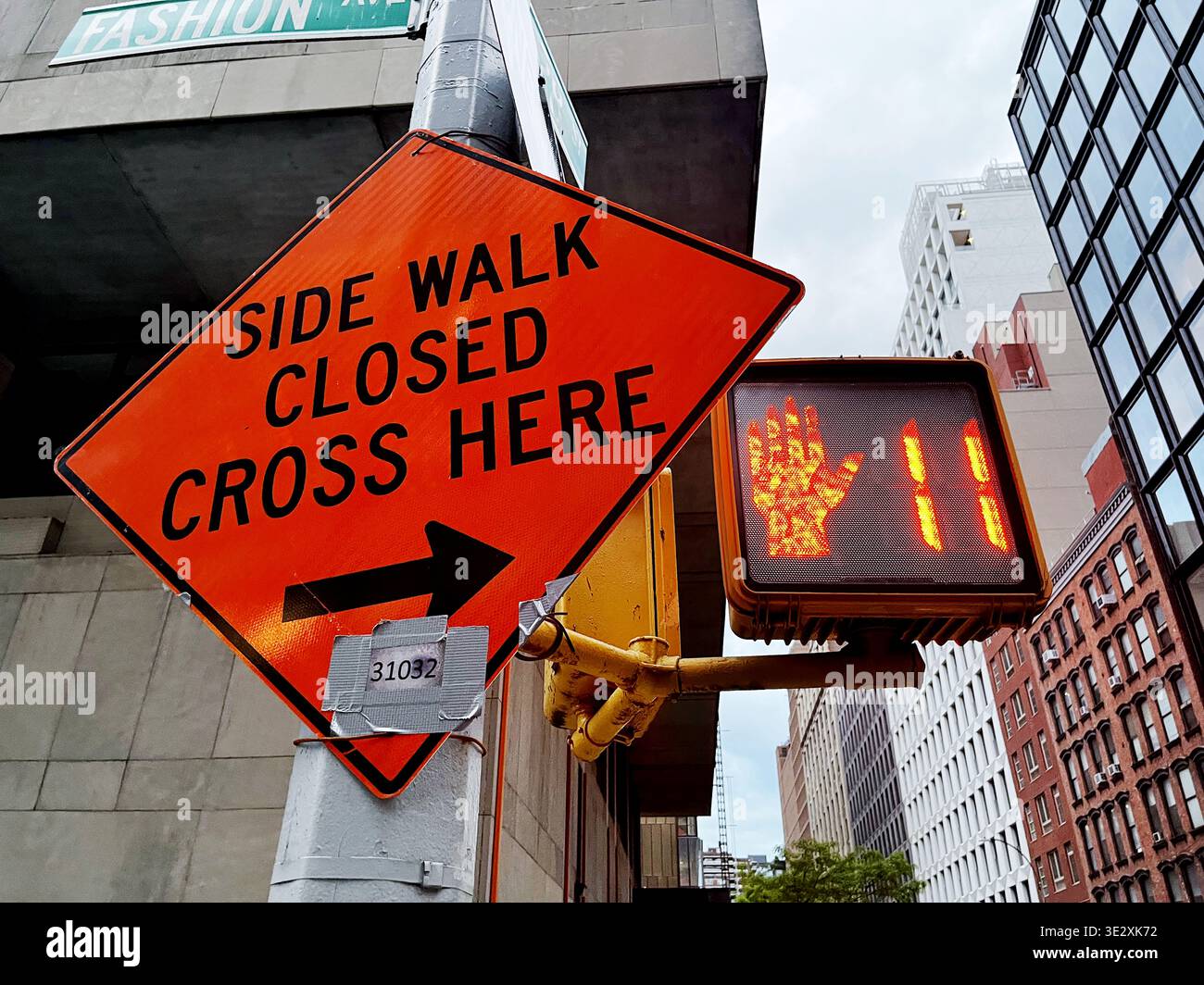 L'image montre un panneau de construction orange indiquant « SIDE WALK CLOSED CROSS HERE » avec une flèche directionnelle pointant vers la droite - New York City - États-Unis - Image de stock capturée avec un smartphone