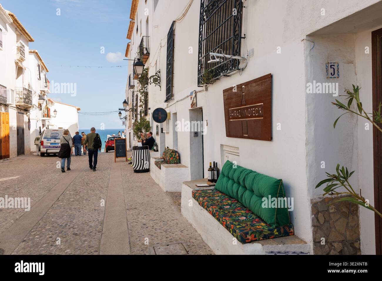 Touristes marchant devant un magasin de vin dans une rue typique d'Altea le 19 mars 2026, Espagne Banque D'Images