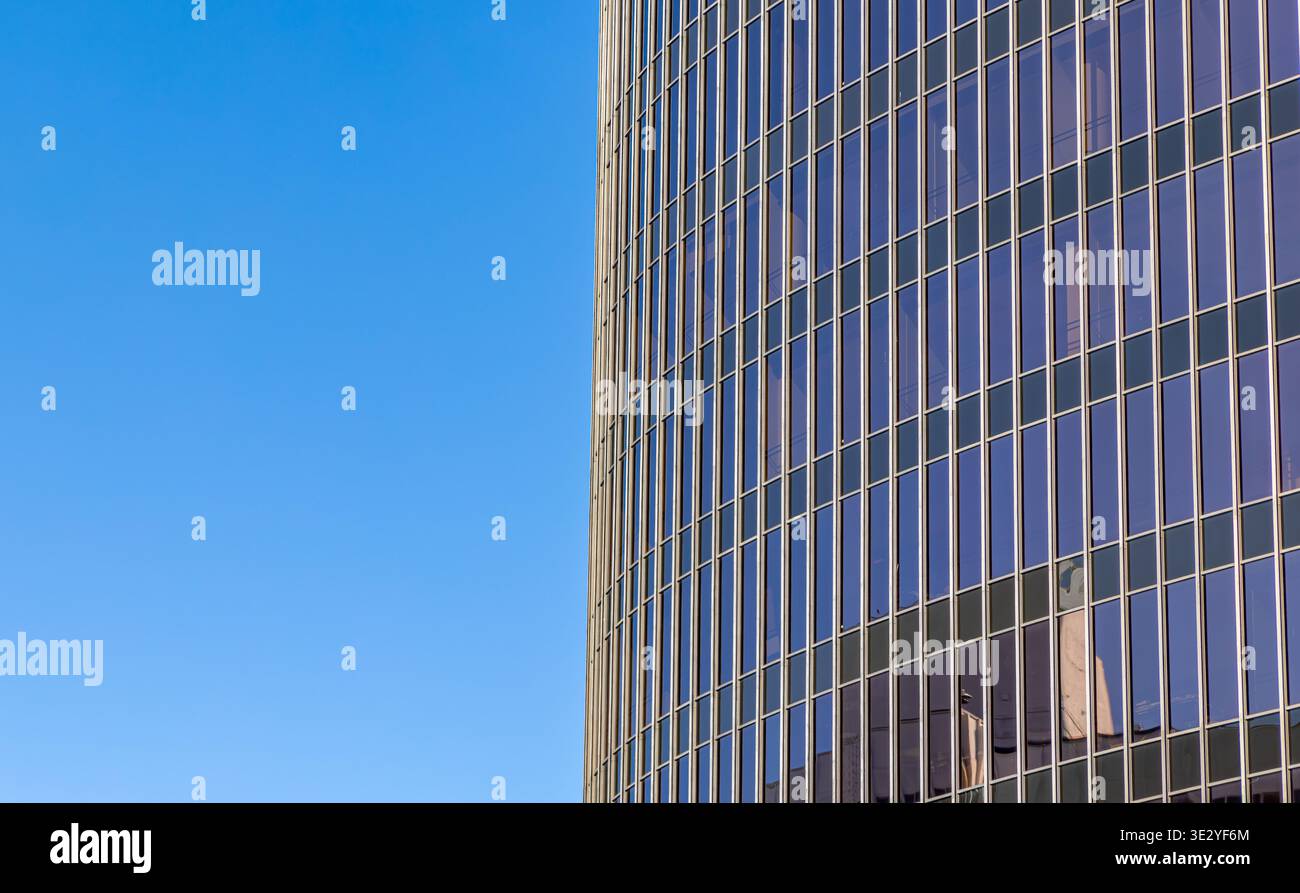 gros plan de l'extérieur d'un gratte-ciel en verre moderne contre un ciel bleu clair Banque D'Images