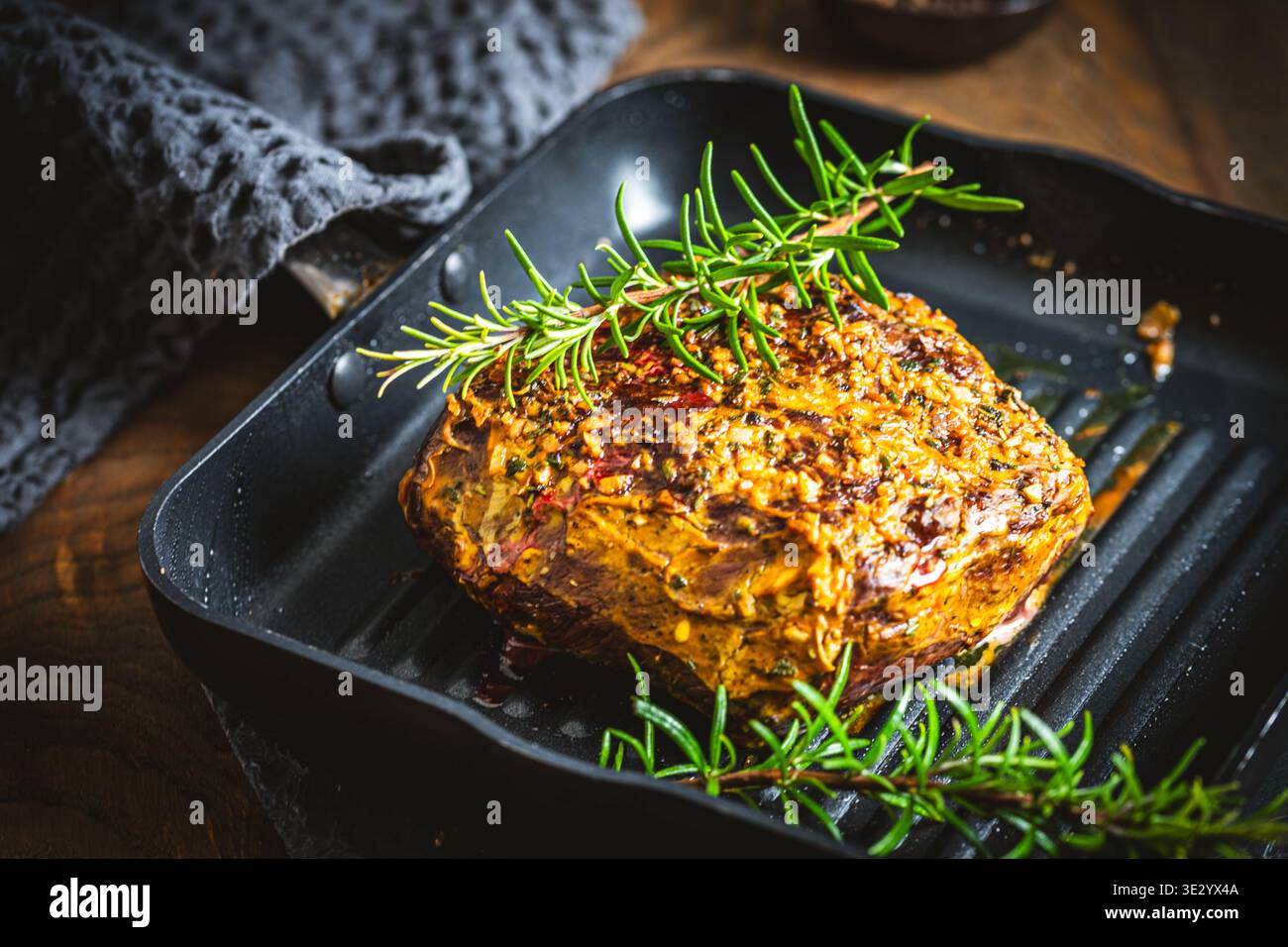 Rôti de bœuf en une seule pièce, servi avec une croûte moutarde-herbe, fraîche du four, sur une table en bois rustique. Banque D'Images
