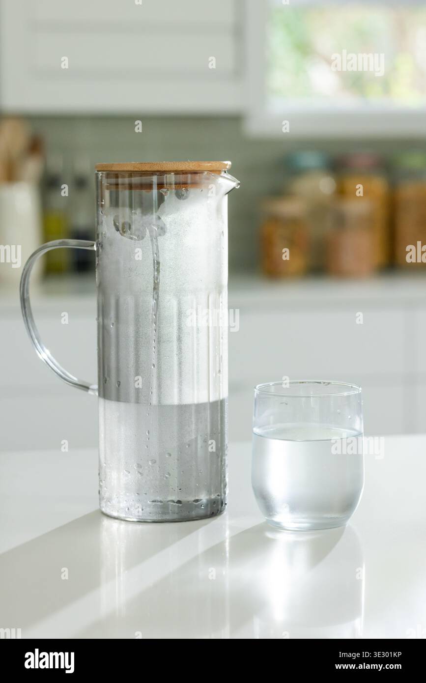 Montrant pichet en verre avec couvercle en bois se condensant et moussant sur le comptoir de cuisine brillant, gobelet Banque D'Images