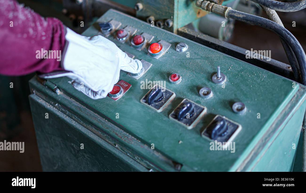 Main gantée appuyant sur les boutons du panneau de commande en usine Banque D'Images