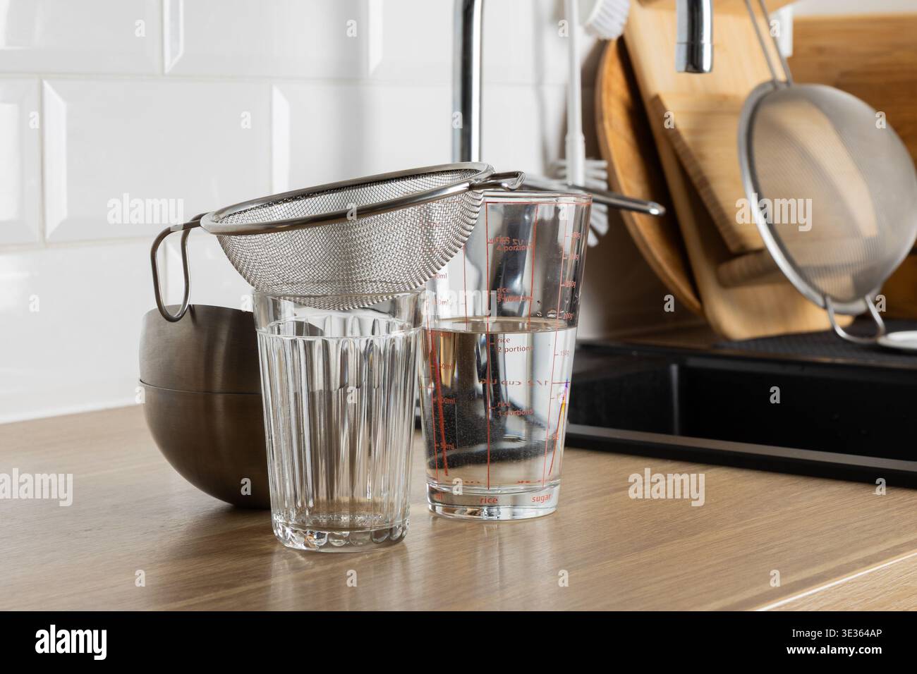 Une scène de cuisine claire avec une passoire et des verres sur un comptoir Banque D'Images
