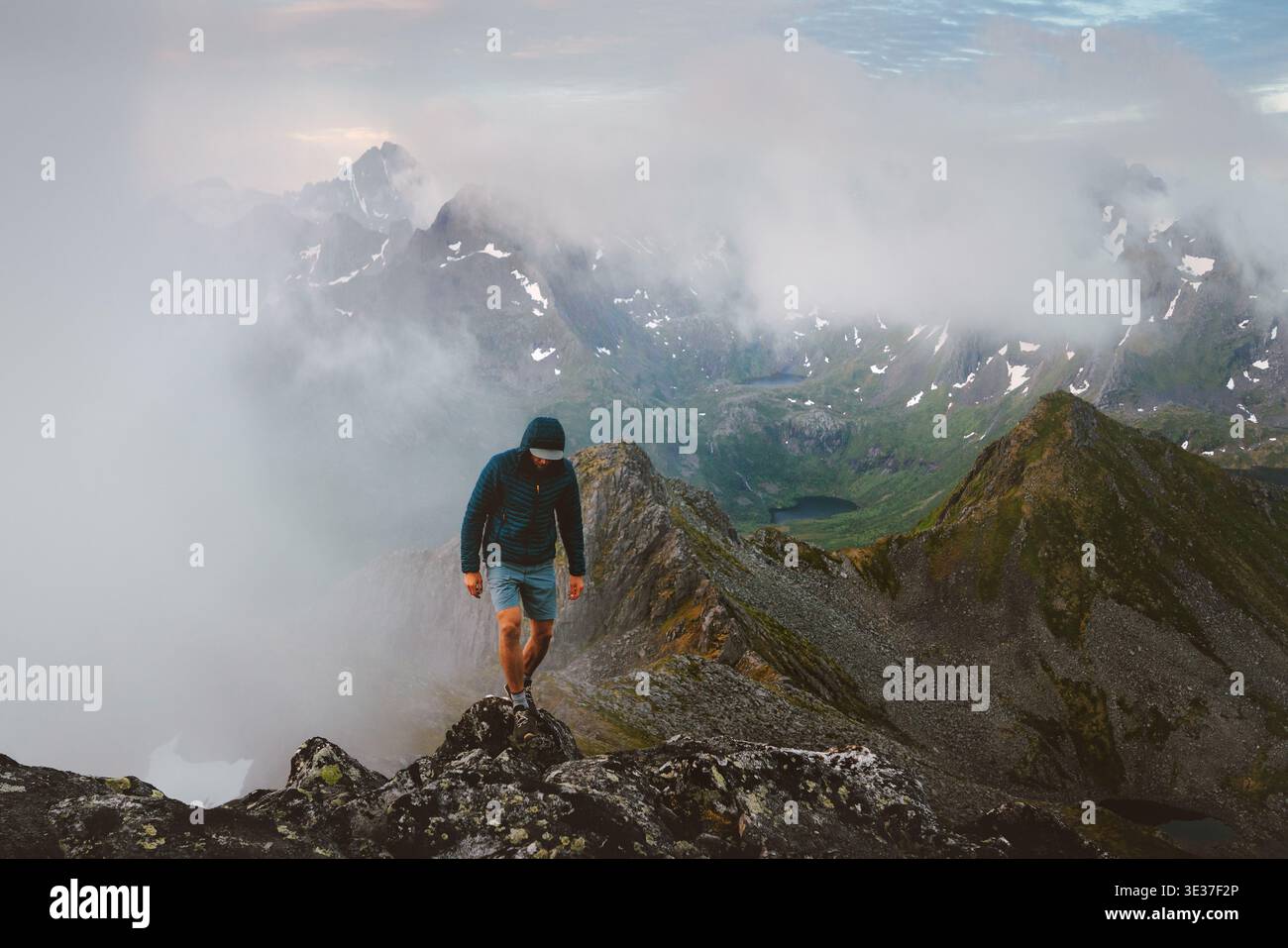 Homme touriste grimpant sommet de montagne brumeuse en Norvège voyage style de vie vacances dans les îles Lofoten aventure voyage plein air style de vie sain, actif tr Banque D'Images