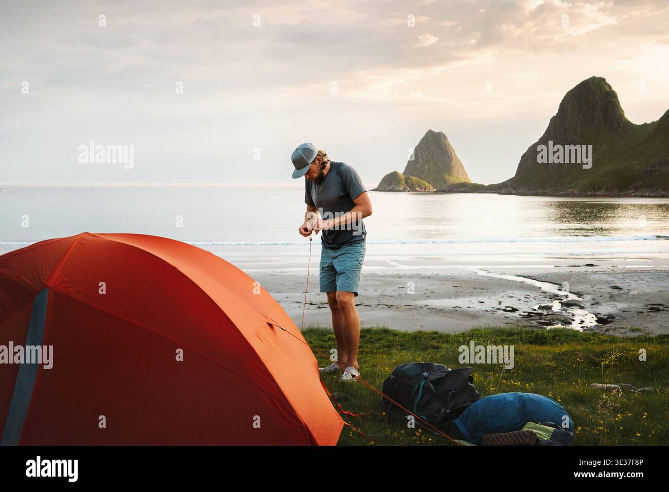 Homme voyageur installant des équipements de camping de tente sur la plage sauvage voyage en Norvège randonnée aventure, style de vie sain actif vacances d'été avec sur Banque D'Images