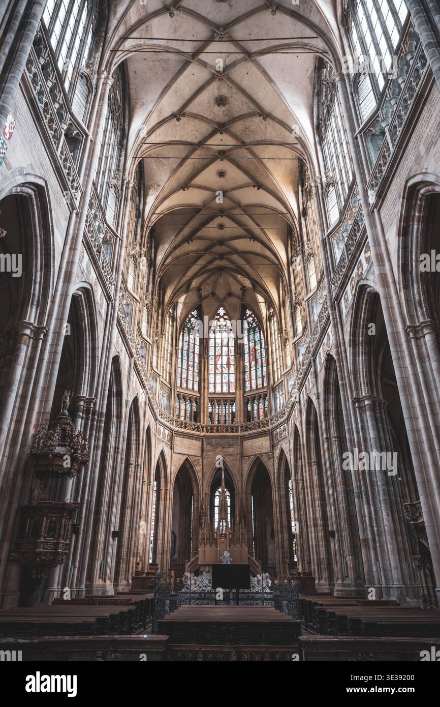 Les visiteurs explorent l'intérieur gothique de la cathédrale de composition Vitus au château de Prague. De grandes arches et des vitraux créent une atmosphère historique dans ce lieu célèbre. Banque D'Images