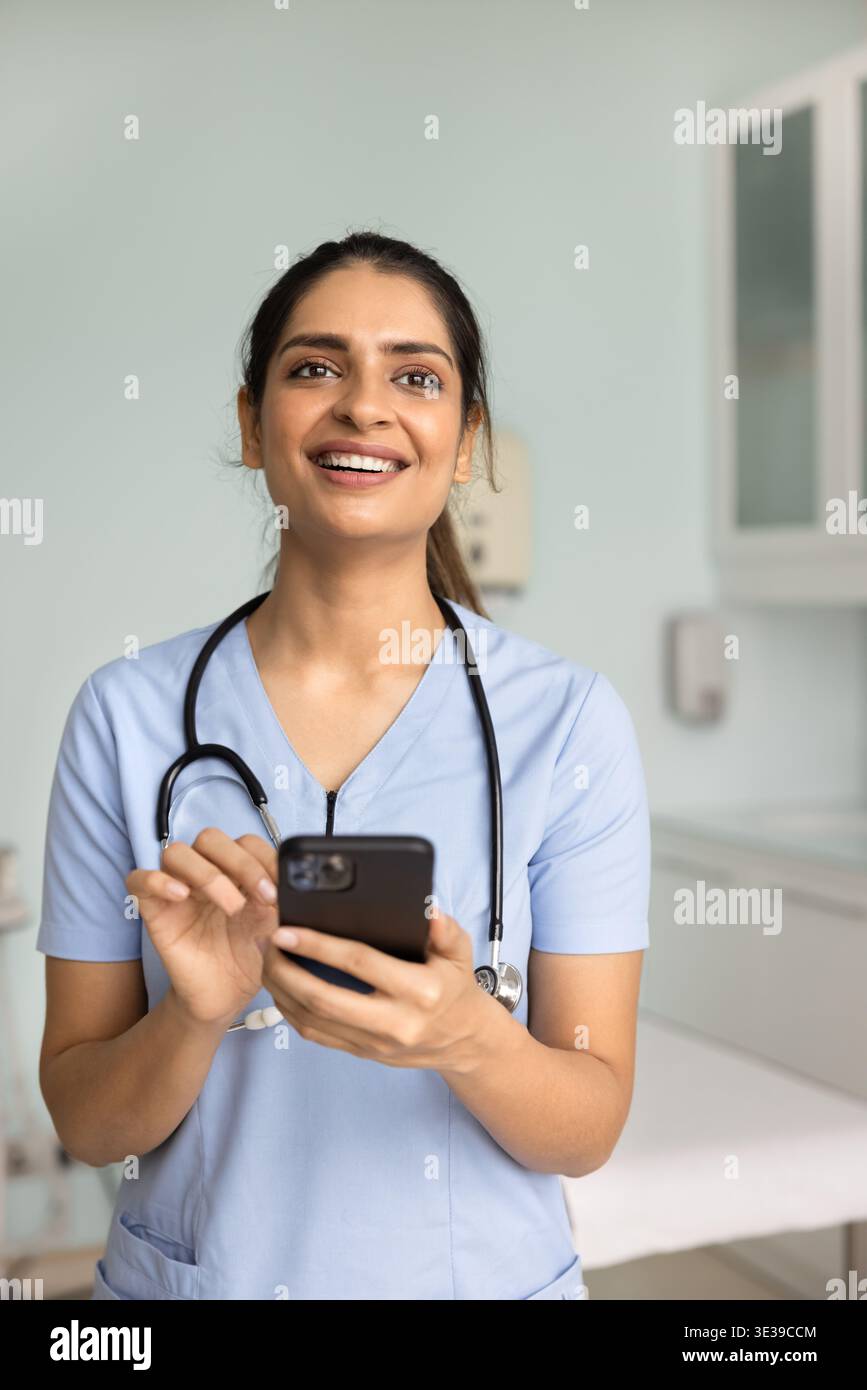 Jeune femme médecin confiante utilisant un smartphone debout à la clinique Banque D'Images