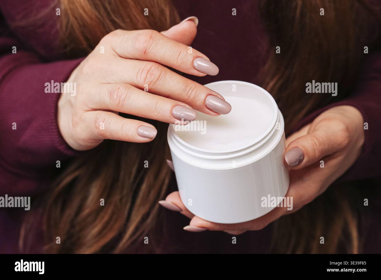 Mains féminines tenant un pot cosmétique blanc. Produit de soin de la peau pour la routine beauté quotidienne. Récipient de crème montré dans une composition de gros plan simple et propre Banque D'Images