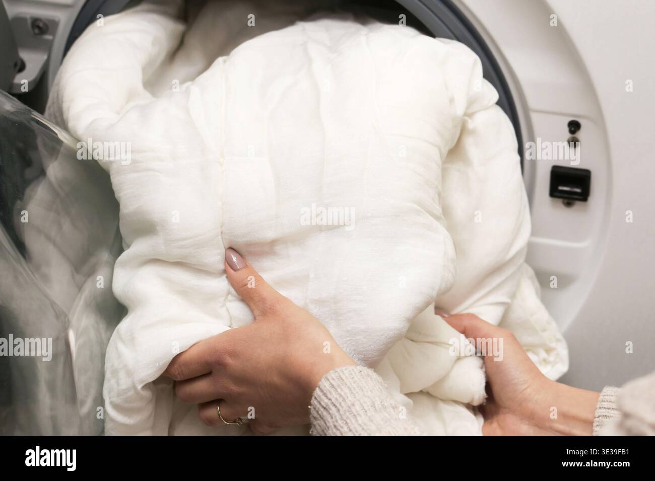 Couette blanche à l'intérieur de la machine à laver. Concept de soin de la lessive et de la literie. Routine de nettoyage de textile domestique doux à la maison moderne. Banque D'Images