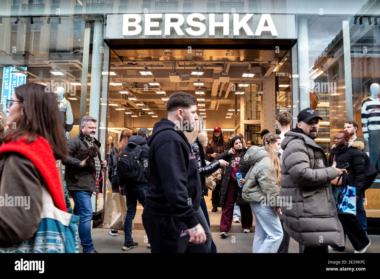 Les consommateurs marchent devant la vitrine Bershka sur Oxford Street, dans le centre de Londres, alors que l'économie britannique reste lente et que l'inflation devrait à nouveau augmenter. Banque D'Images
