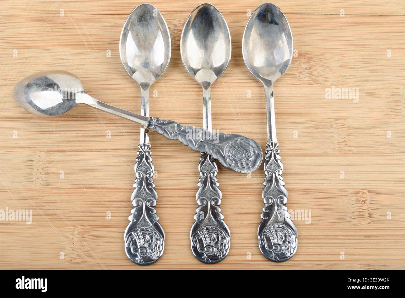 Cuillères à café plaquées argent vintage avec des motifs complexes sur bois. Banque D'Images
