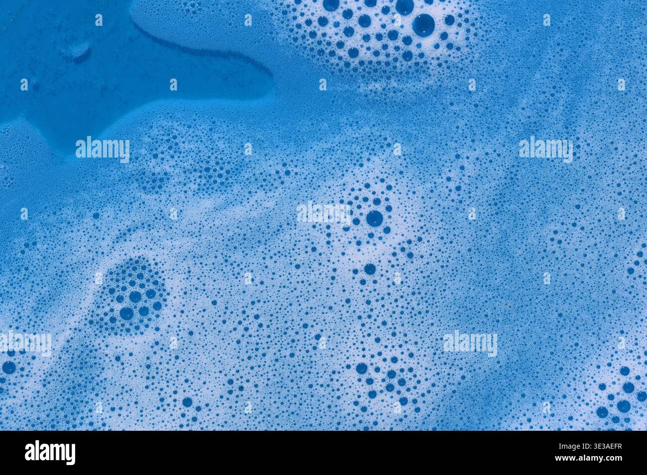 Gros plan d'eau savonneuse bleue avec des bulles créant un arrière-plan texturé tourbillonnant Banque D'Images