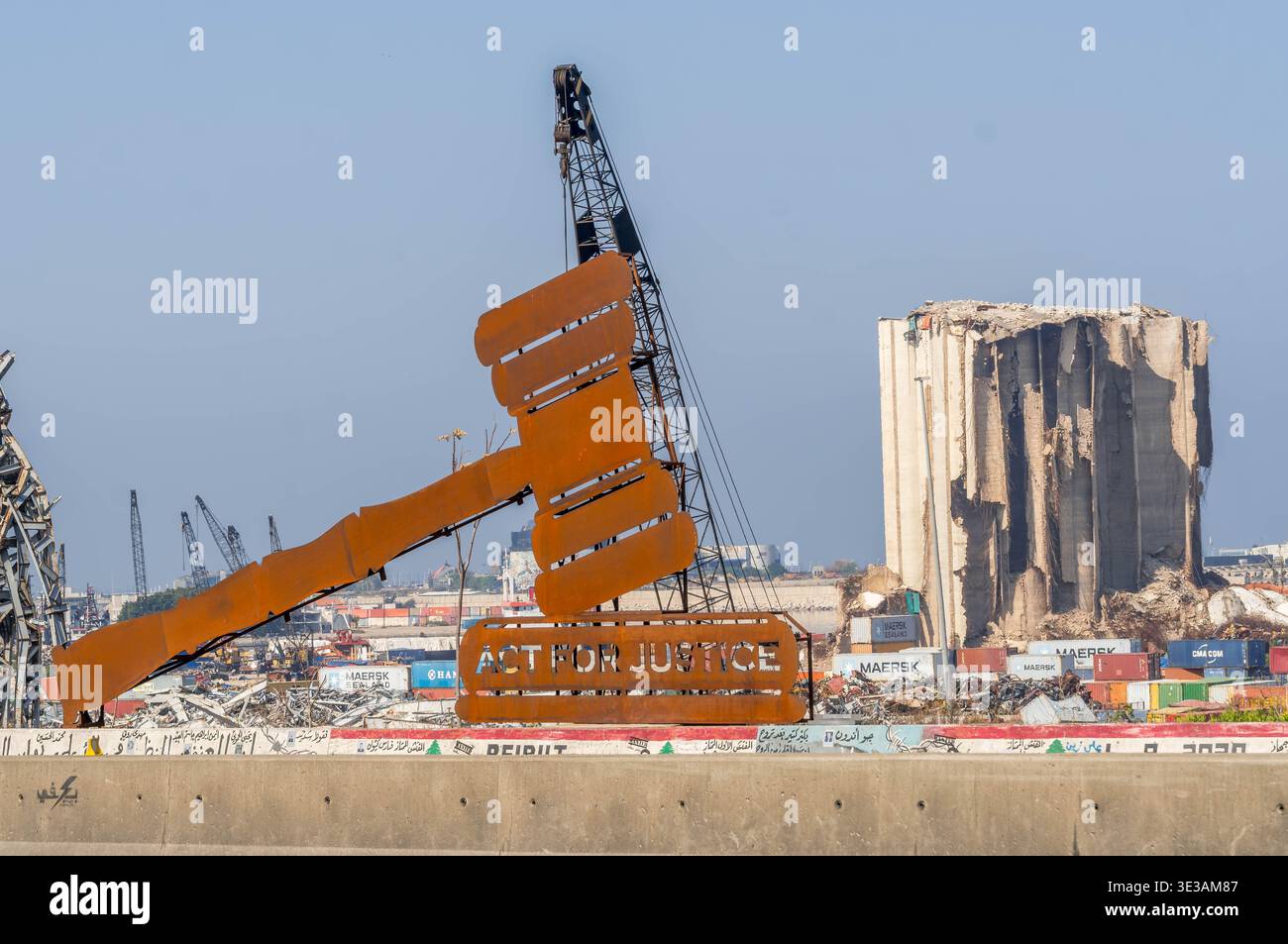 Panneau de protestation avec « AGIR POUR LA JUSTICE » encadrant le silo à céréales endommagé lors de l'explosion du port de Beyrouth en 2020 au Liban. Banque D'Images