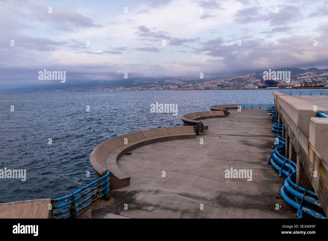 Promenade méditerranéenne le long de la corniche de Beyrouth avec grues portuaires lointaines et collines du Mont Liban en arrière-plan, Beyrouth. Banque D'Images