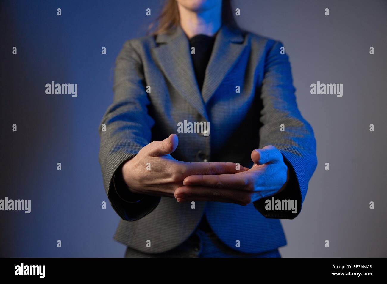 Un portrait d'une femme sans visage en costume d'affaires, tenant sa main en avant. Correction de la couleur bleue Banque D'Images