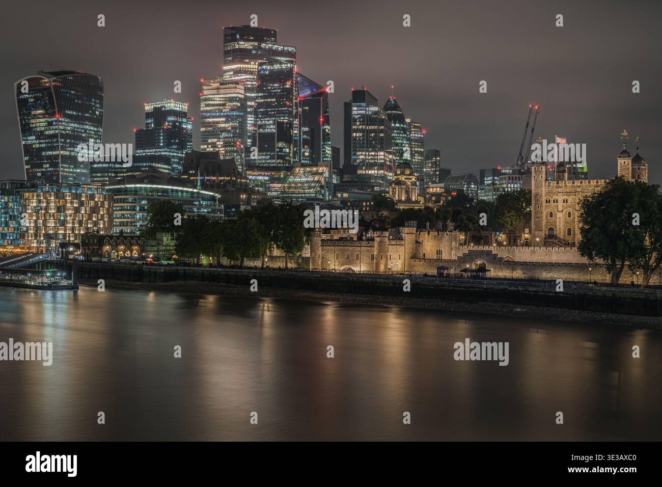 La Tour de Londres illuminée la nuit avec les gratte-ciels modernes de la City de Londres derrière Banque D'Images