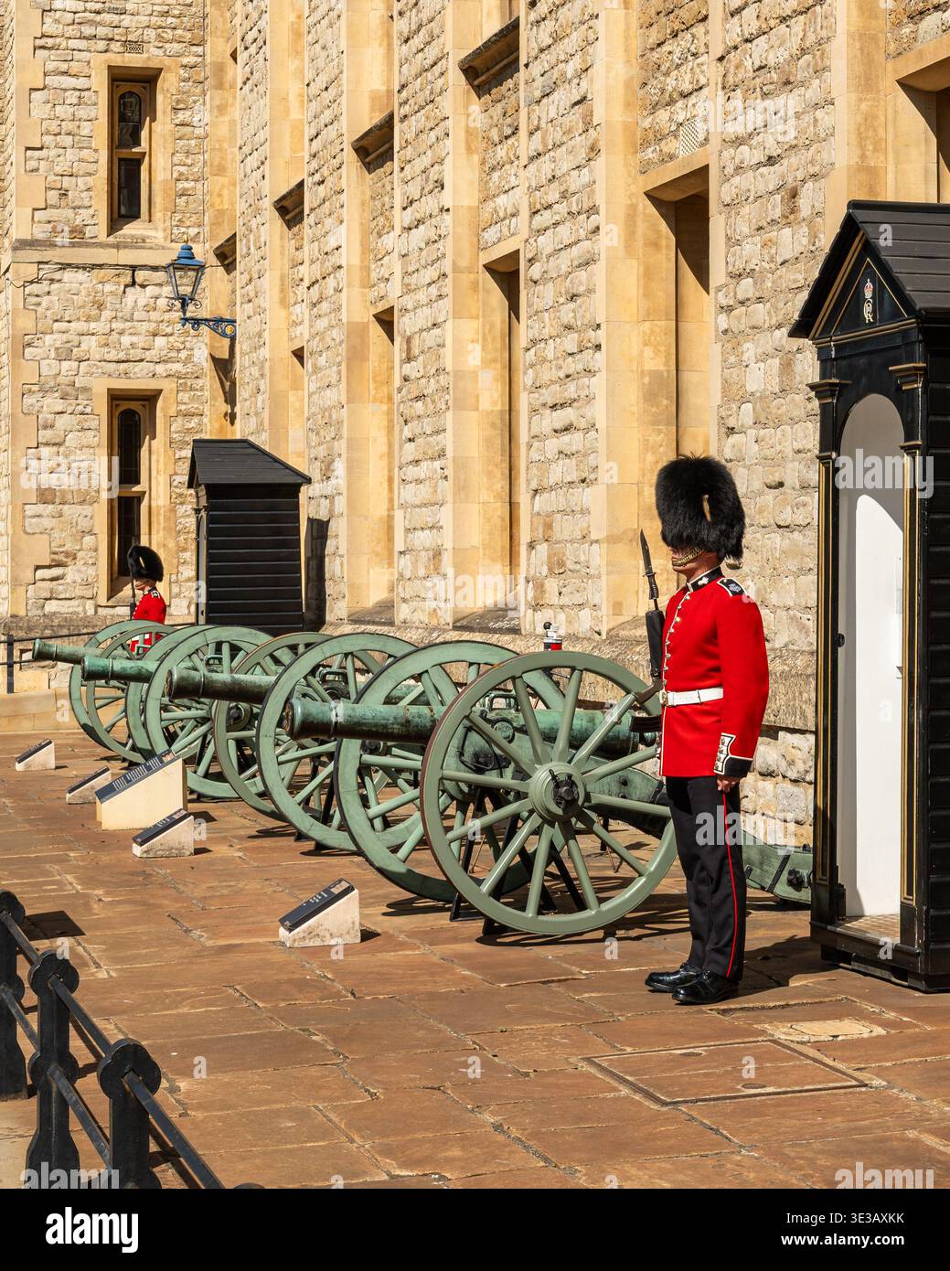 Une garde royale en uniforme rouge traditionnel debout près des canons à la Tour de Londres Banque D'Images