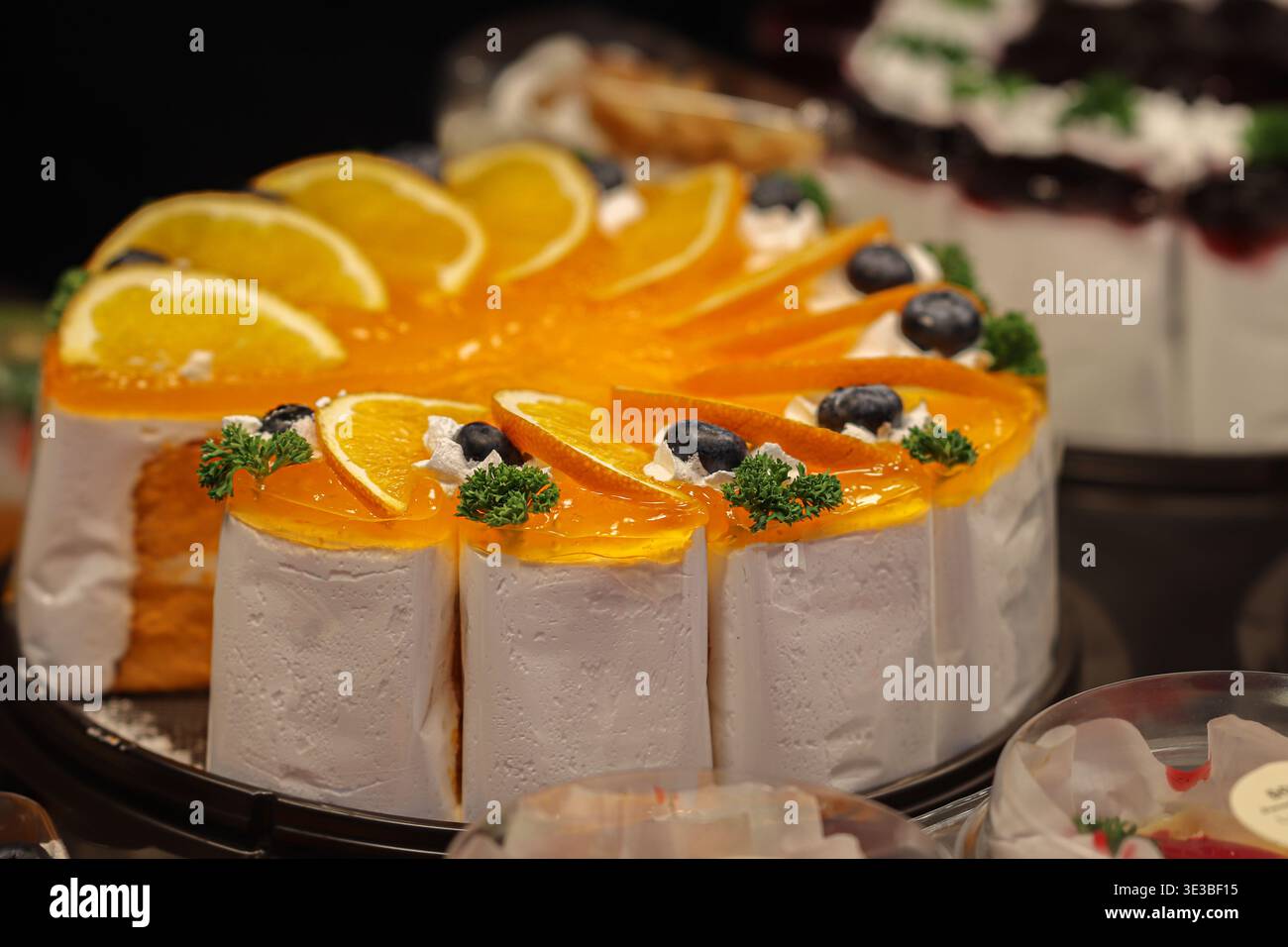Tranches de gâteau en mousseline d'orange avec orange fraîche et bleuets montrant un dessert de boulangerie dynamique et un style café. Banque D'Images