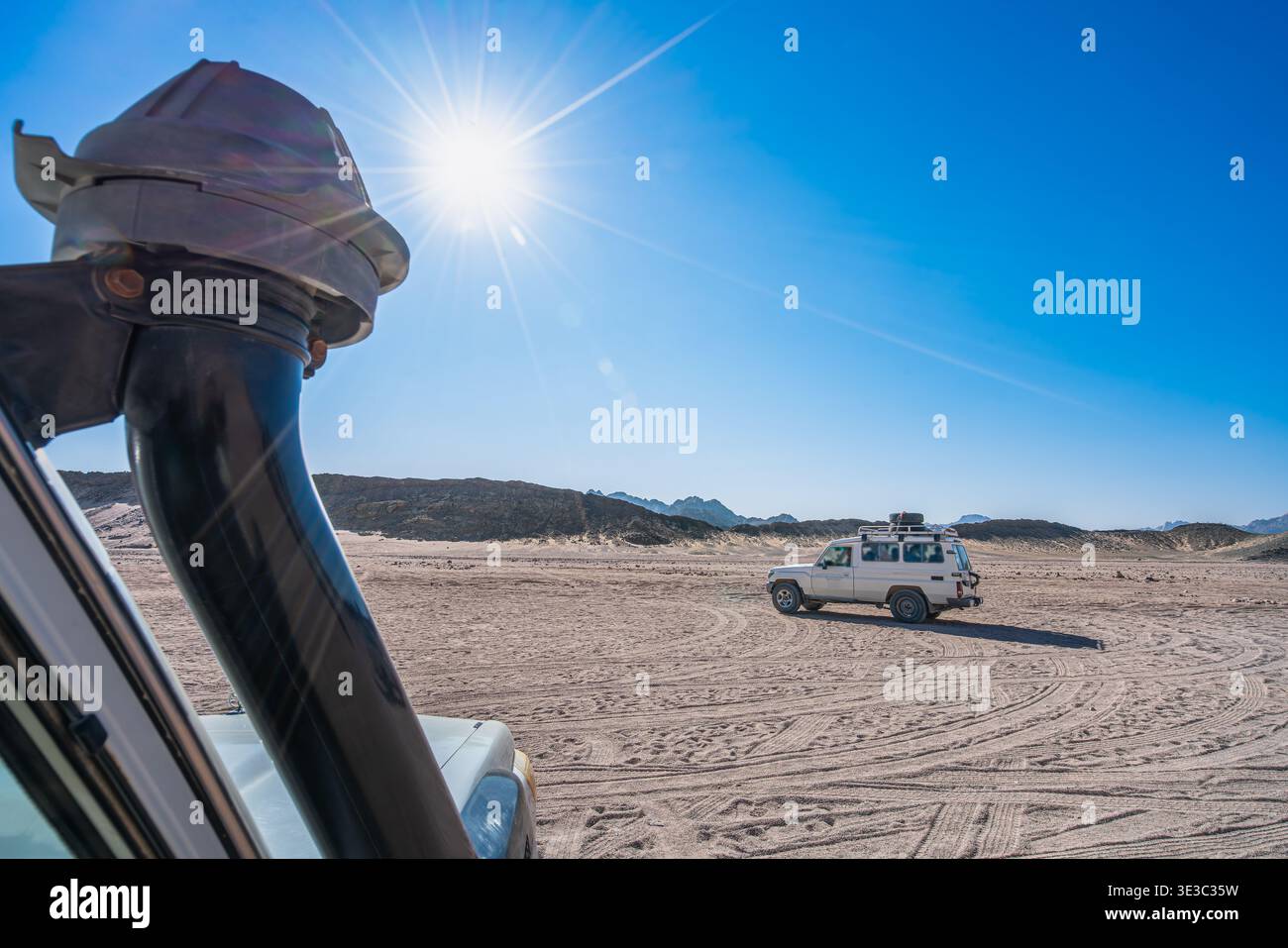 Une vue de l'intérieur d'un véhicule 4x4 regardant une jeep blanche hors route dans le vaste paysage ensoleillé du désert du Sahara près de Hurghada, en Égypte. Banque D'Images
