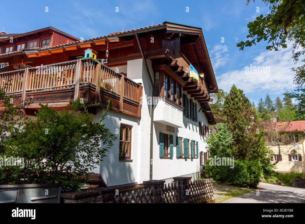 Maison bavaroise traditionnelle à Fussen avec un drapeau ukrainien sur le balcon. Architecture alpine typique avec balcon en bois et volets verts sur un soleil Banque D'Images