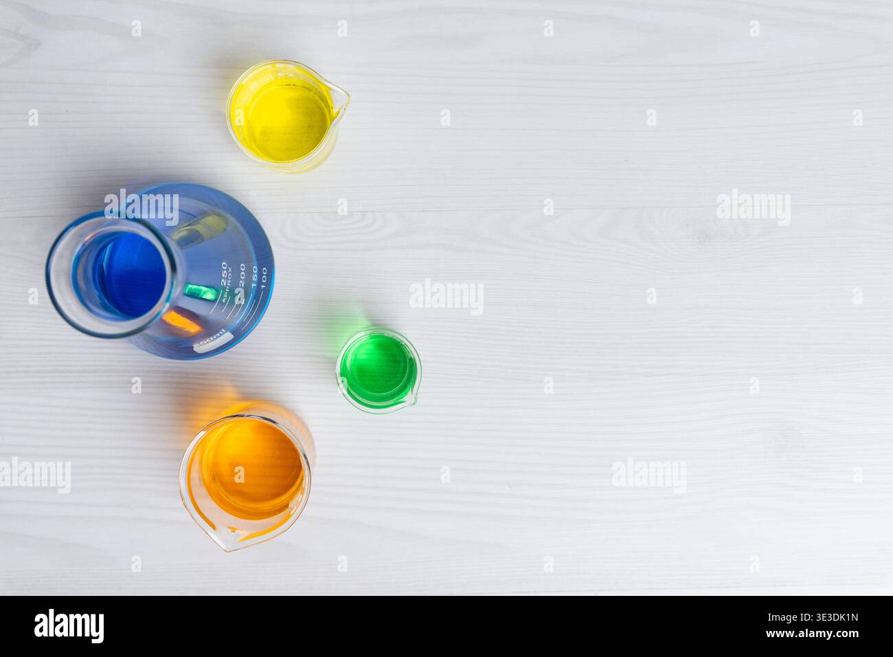 liquides de laboratoire colorés en verrerie disposés sur une surface blanche représentant la recherche en chimie, l'innovation et le concept de conception scientifique Banque D'Images