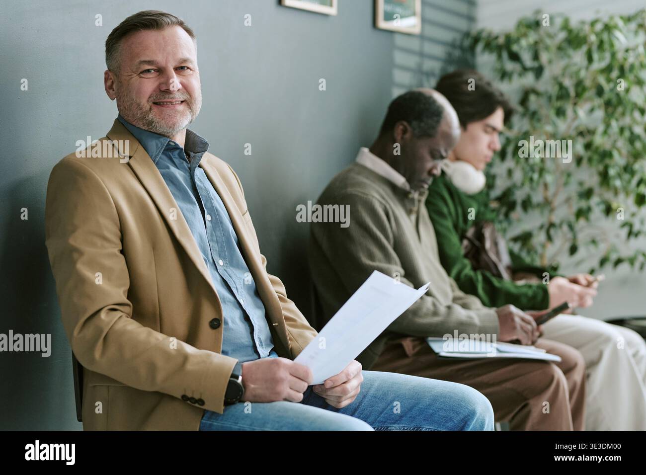 Portrait d'homme caucasien d'âge moyen souriant en attendant dans la succursale bancaire Banque D'Images