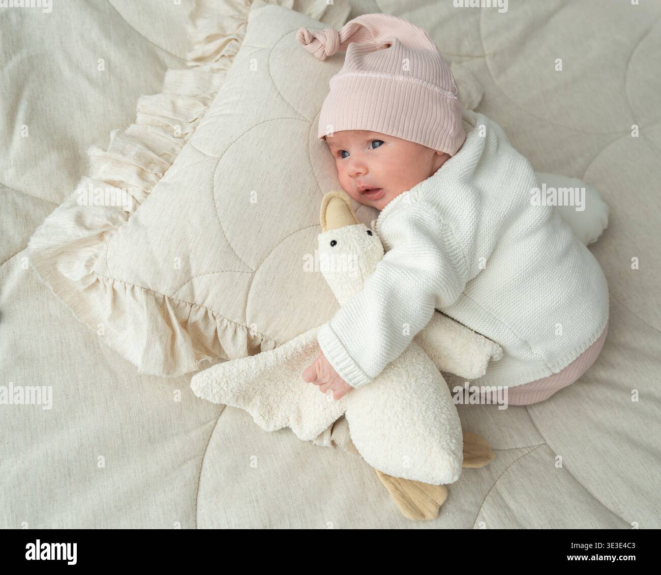 Bébé nouveau-né se reposant tout en embrassant un jouet en peluche doux sur fond de tissu neutre. Scène de style de vie douce pour les parents, le confort de bébé, la sécurité émotionnelle Banque D'Images