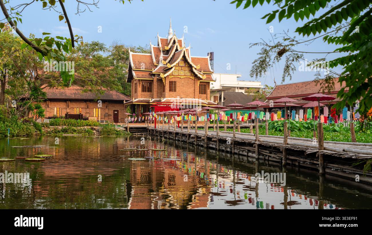 Chiang mai, Thaïlande – 3 mars 2020 : le temple Wat Chet Lin et une passerelle en bois avec des parapluies colorés se reflètent dans un étang sur le terrain du temple. Banque D'Images