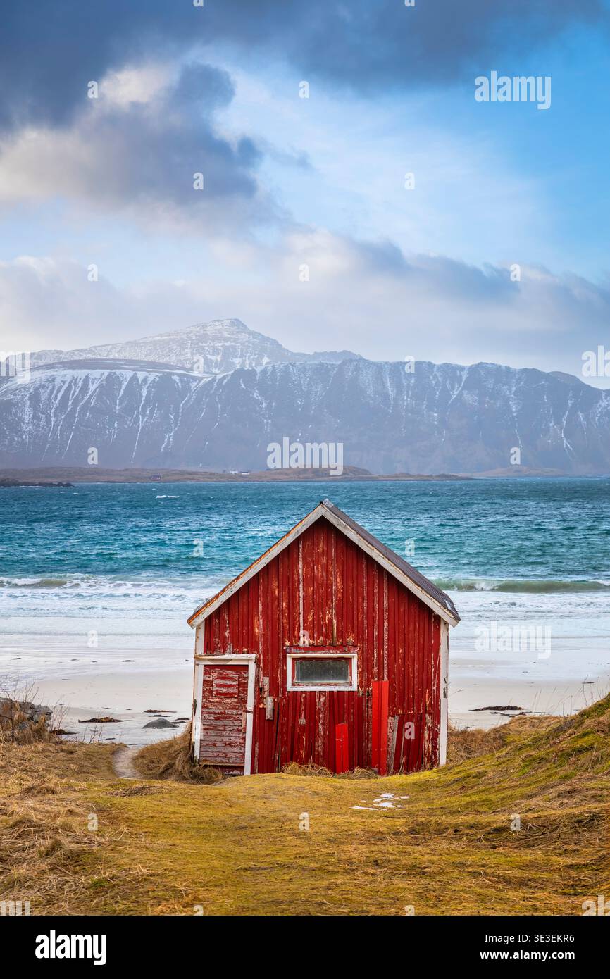 Cabane rouge typique sur la plage de Rambergstranda au coucher du soleil en hiver. Flakstadoya, Nordland, Lofoten, Norvège, Europe du Nord. Banque D'Images