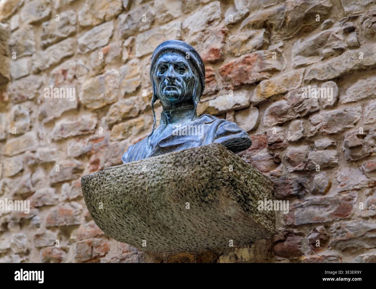 Florence, Italie - 4 juin 2022 : buste en bronze du poète Dante Alighieri sur un piédestal en pierre brute monté sur un mur de roche altérée à l'extérieur de sa maison Banque D'Images