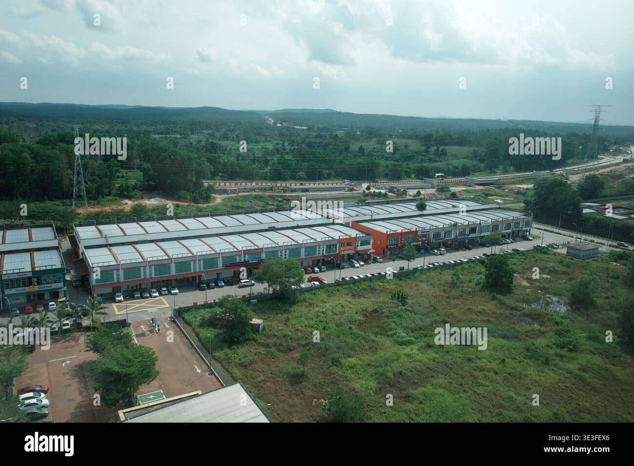 Vue aérienne d'une rangée de bâtiments commerciaux. De longues structures basses avec des toits métalliques bordent une route. Les champs verts s'étendent au-delà du développement. Scattere Banque D'Images