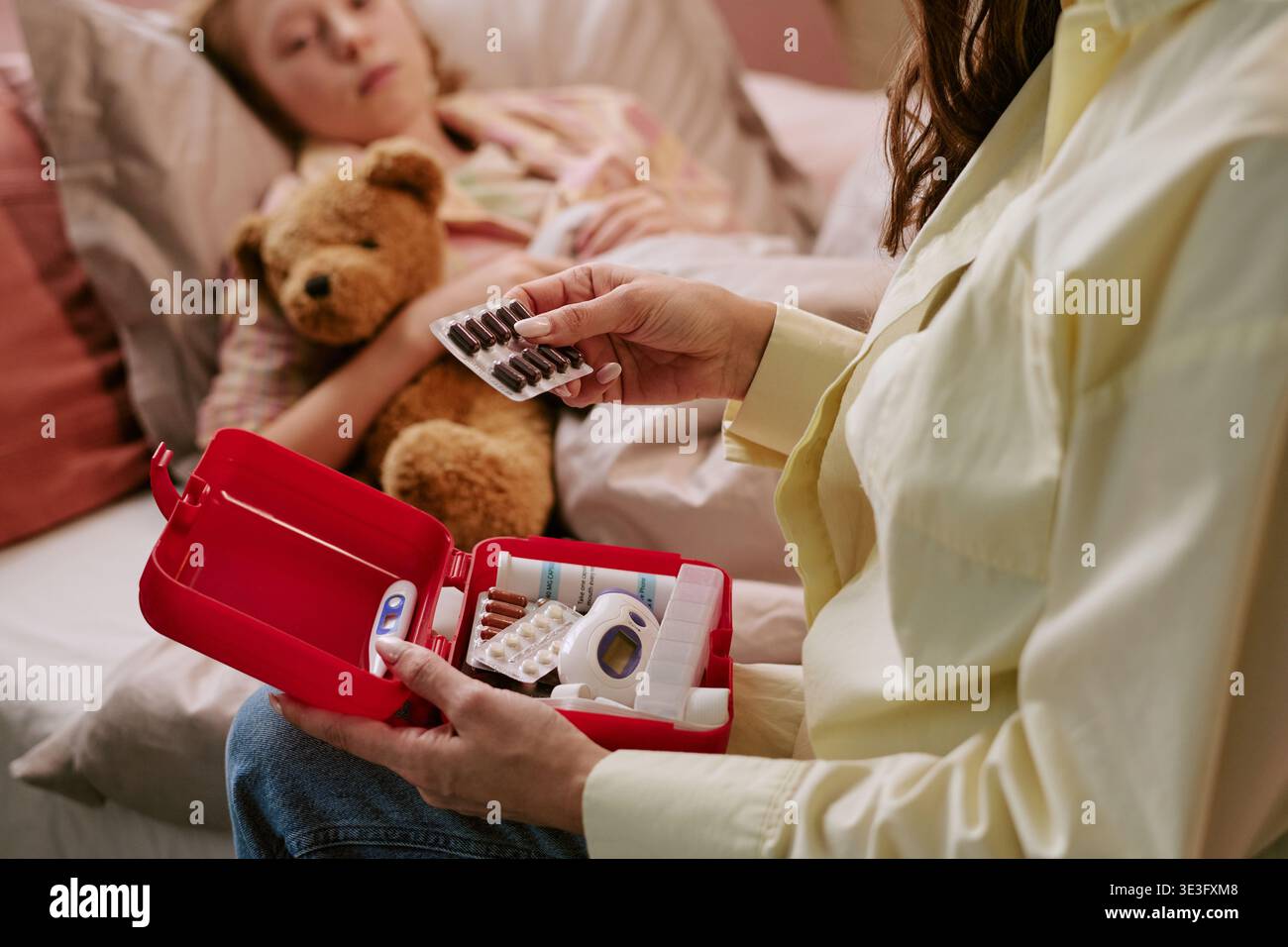 Femme préparant des médicaments pour enfant malade se reposant dans le lit Banque D'Images