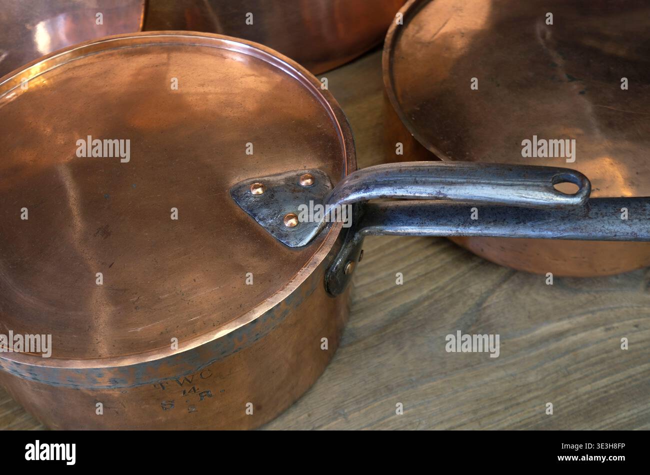 vieilles casseroles en cuivre sur le dessus de table de cuisine en bois, norfolk, angleterre Banque D'Images