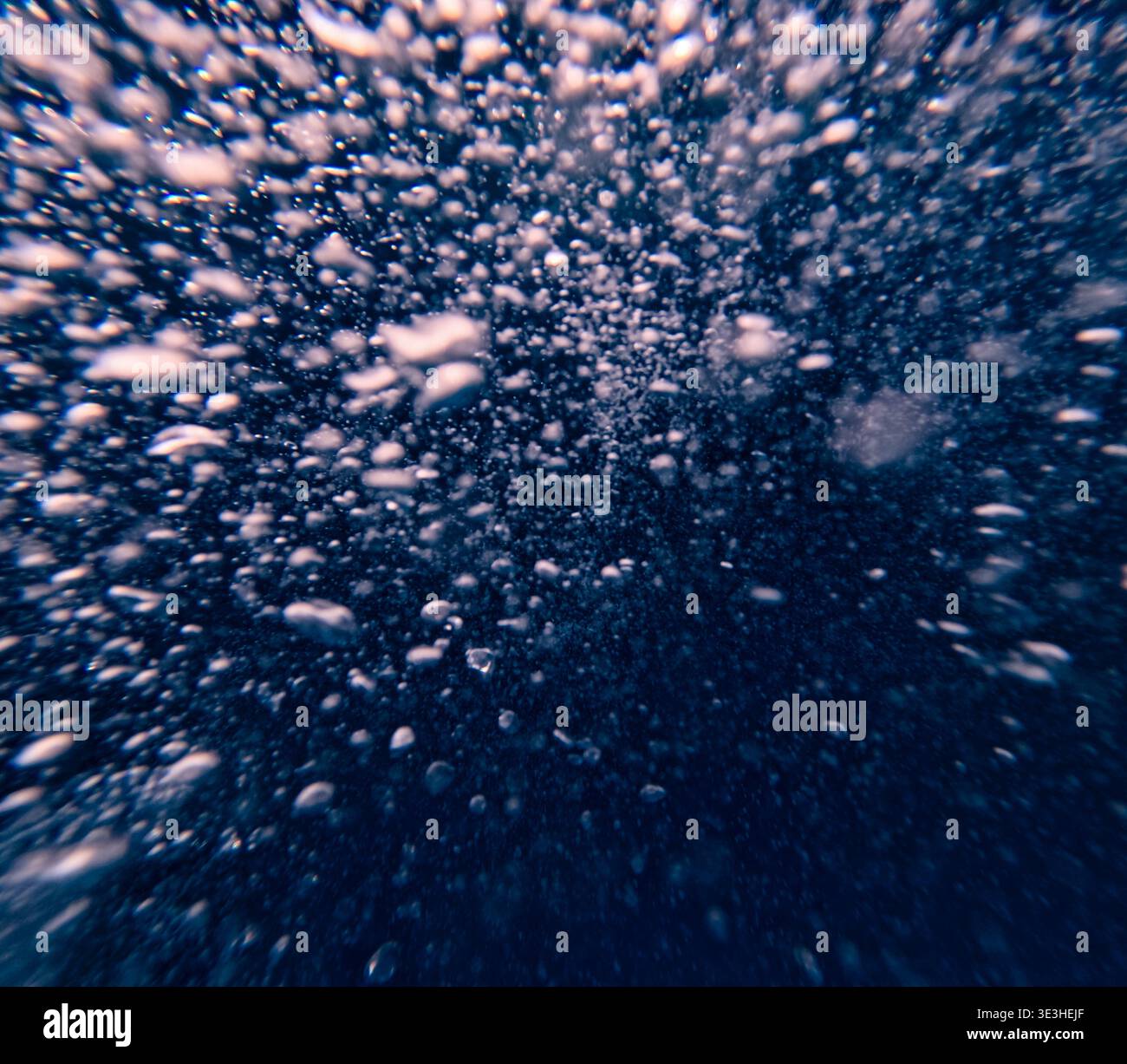 Les bulles d'air s'élèvent sous l'eau dans l'eau bleue profonde créant un arrière-plan abstrait vu de sous la surface Banque D'Images