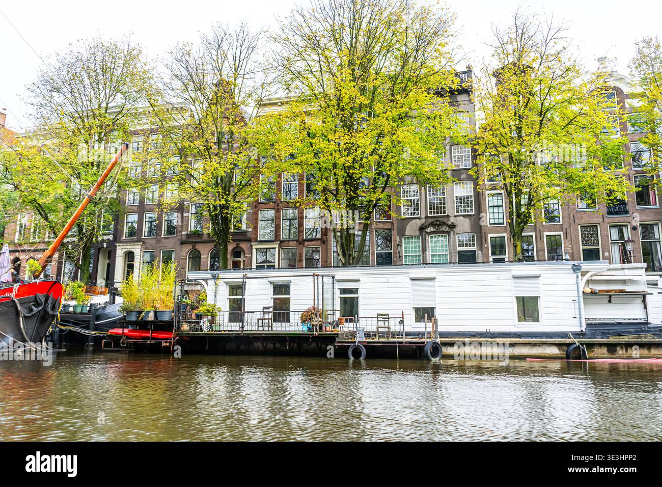 Canal d'Amsterdam avec Houseboat Maison flottante traditionnelle bâtiment. Retour en bateau sur l'eau aux pays-Bas. Arbres extérieurs Banque D'Images