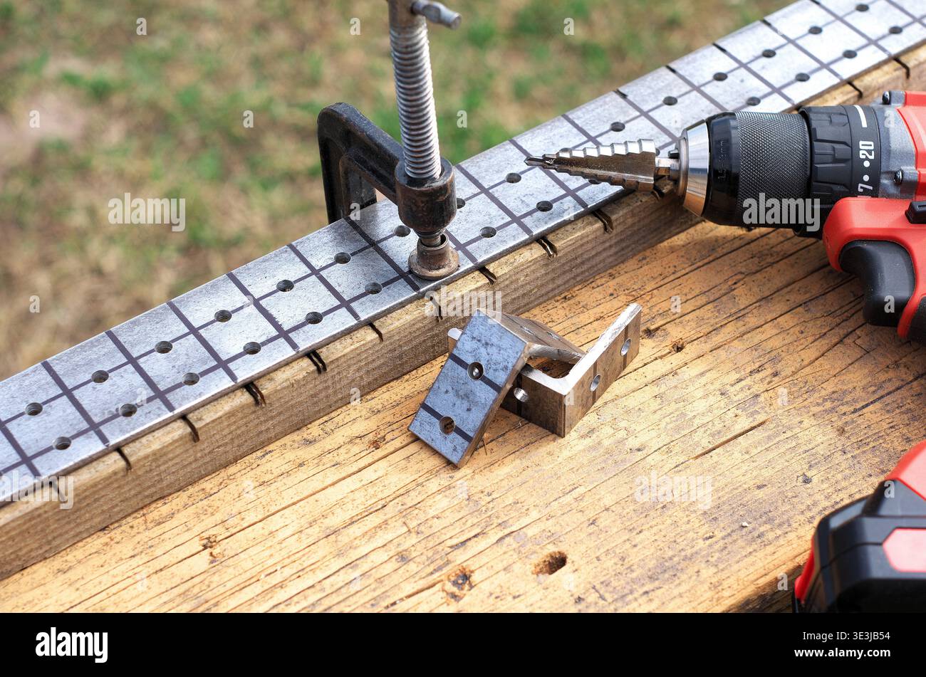 Fabrication de supports de clôture. Pièces à usiner, pinces et tournevis sur un établi. Perçage de trous dans le métal. Foret étagé dans un tournevis. Banque D'Images