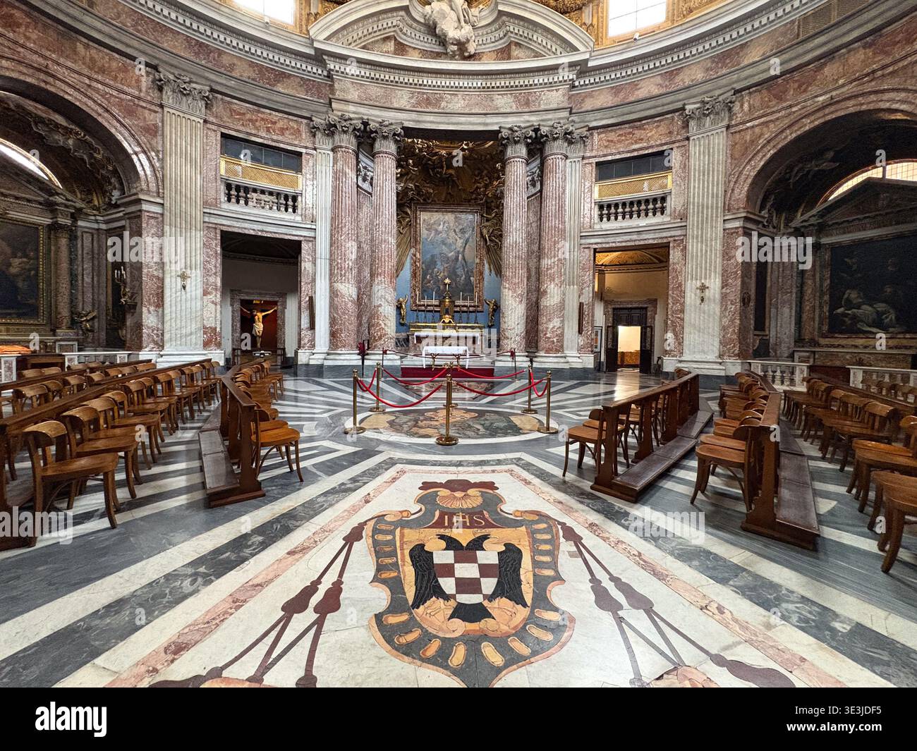 Chiesa di Sant'Andrea al Quirinale. Rome, Italie. Intérieur de l'église baroque avec marbre rouge, bancs en bois et écusson au sol. Banque D'Images