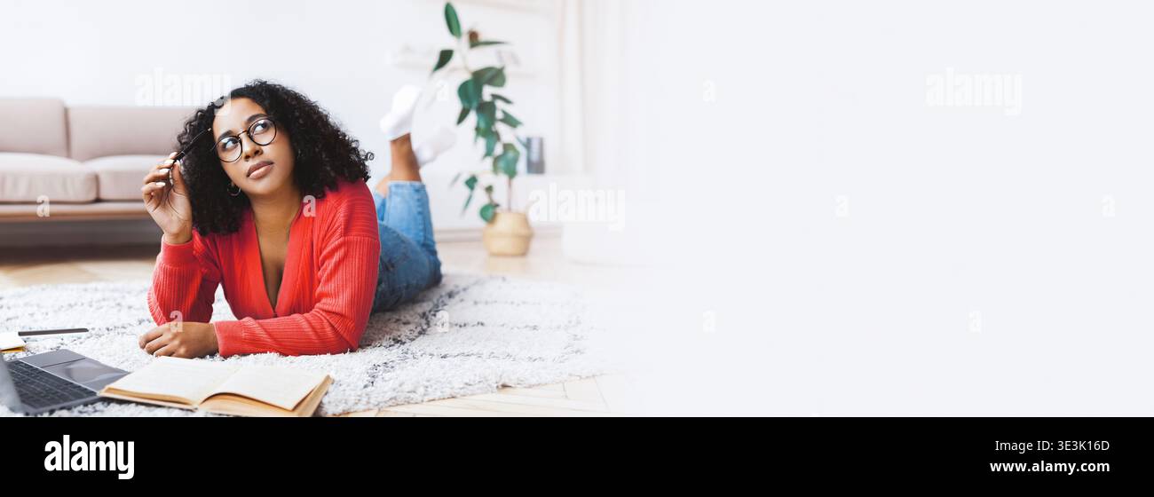 Les étudiants étudient tout en étant allongés sur le sol dans un salon confortable avec des plantes autour Banque D'Images