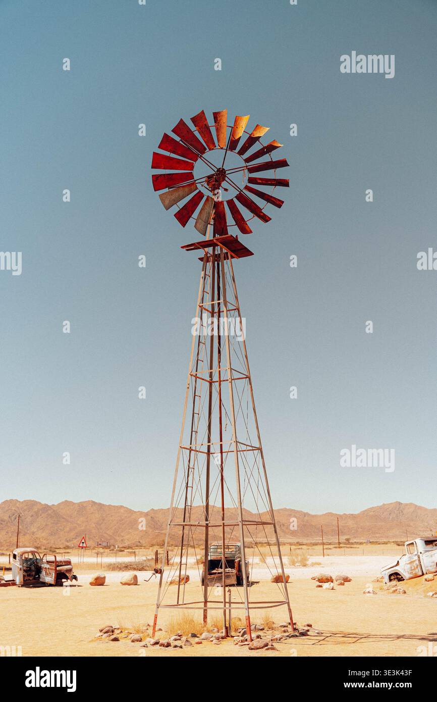 Vue d'un moulin à vent rouillé se dresse contre le paysage aride, avec ses lames attrapant le soleil, en Namibie, Afrique, Namibie. Banque D'Images