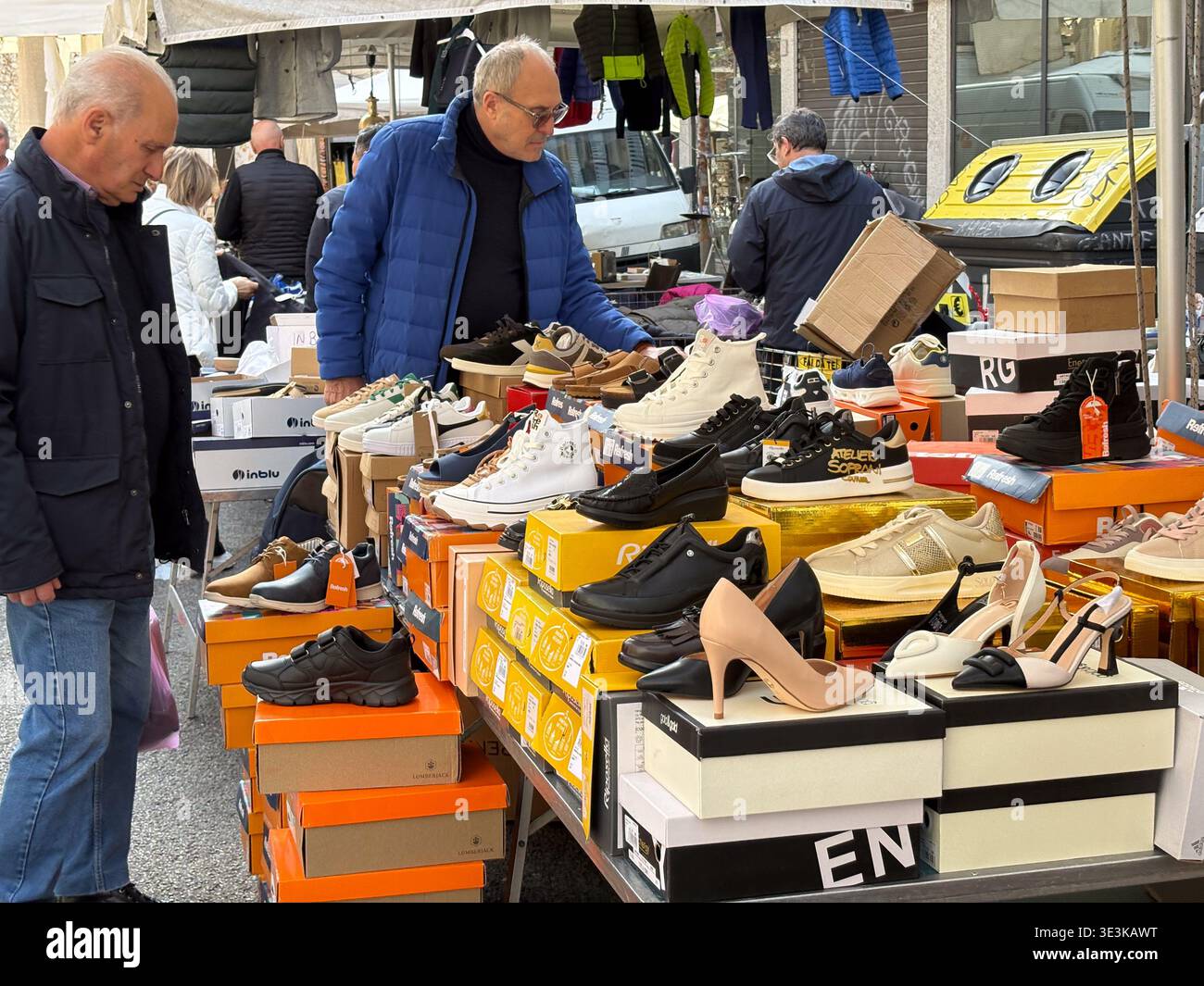 Marché aux puces de Porta Portese, Rome, Italie. Les acheteurs examinent divers styles de chaussures, y compris les baskets et les talons exposés sur les boîtes à l'extérieur. Banque D'Images