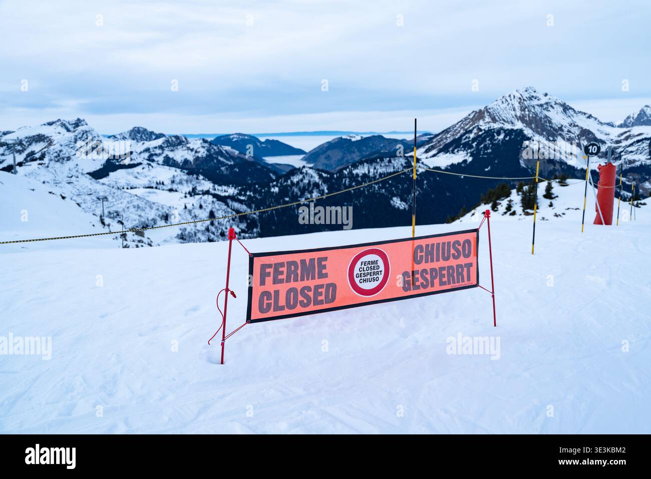 Vue d'une piste de ski fermée avec un panneau orange vif affichant 'ferme fermée Chiuso Gesperrt' sur fond de montagnes enneigées, Val-d'Illie Banque D'Images
