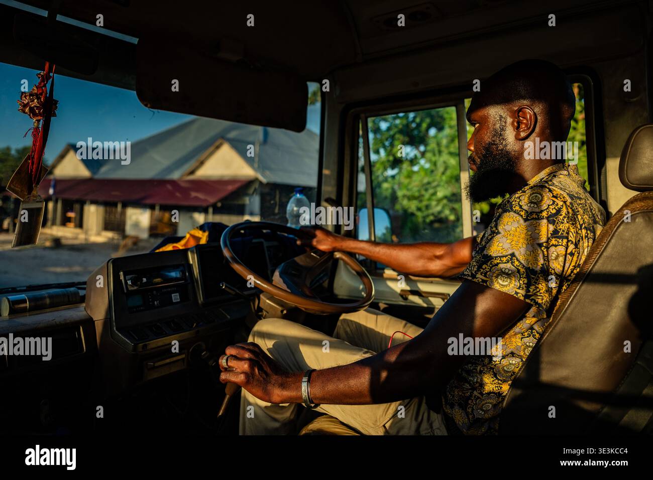PAJE, ZANZIBAR - 18 OCTOBRE 2025 : un Africain local conduisant un bus à travers un village de Zanzibar, capturé à la lumière chaude de l'heure d'or à travers le camion Banque D'Images