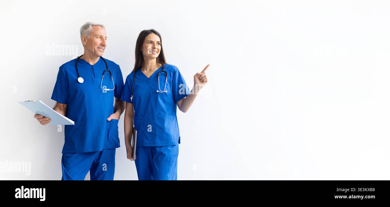Professionnels de santé masculins et féminins dans des gommages bleus pointant vers l'espace de copie Banque D'Images