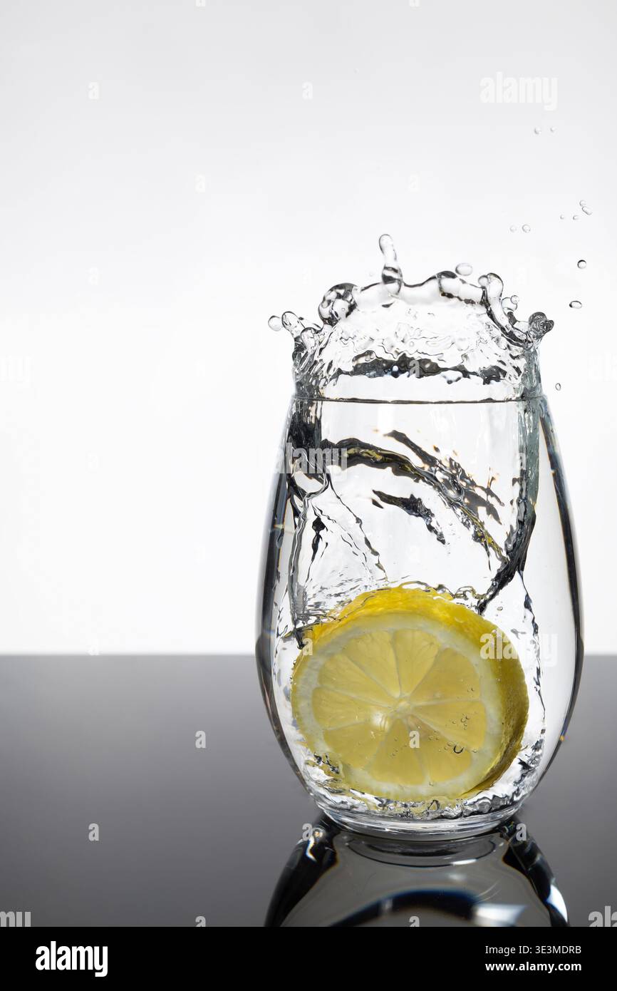 Tranche de citron éclaboussant dans un verre d'eau – Citrus Motion Shot frais Banque D'Images
